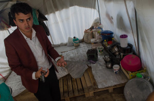 The inside of one family's tent, where shipping palettes raise the floor above mud and rainwater.